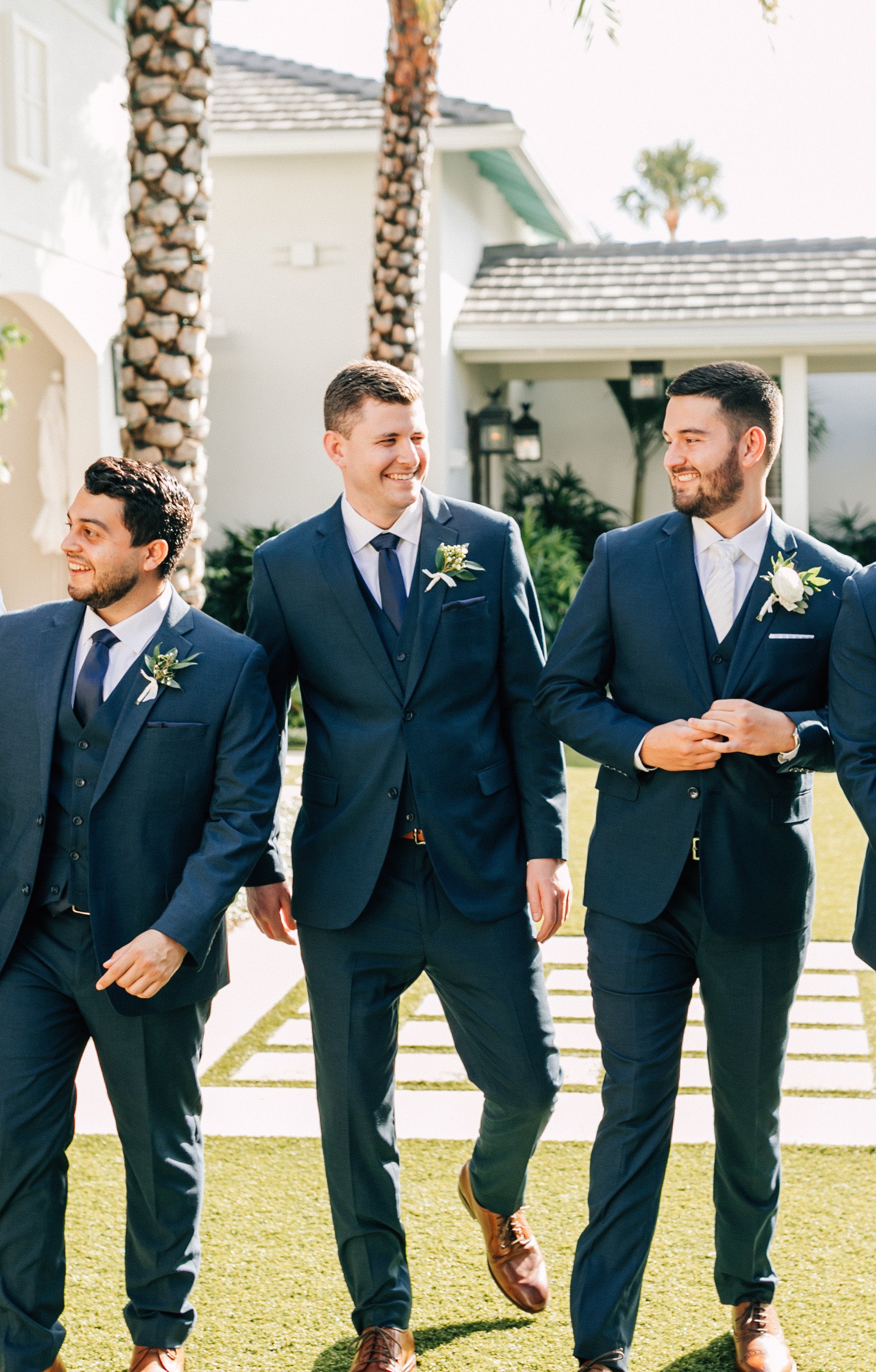 A group of men in suits for fall laugh together at a wedding