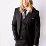 A blonde male groomsman wears a black suit by Modern Groom.