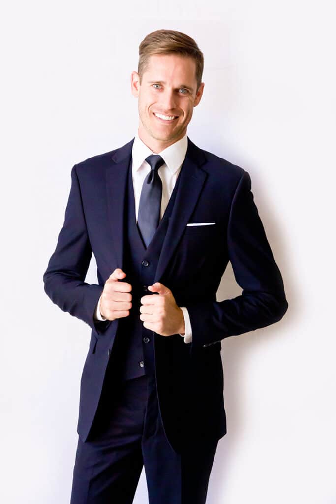 Smiling male model posing in a navy suit for Modern Groom.