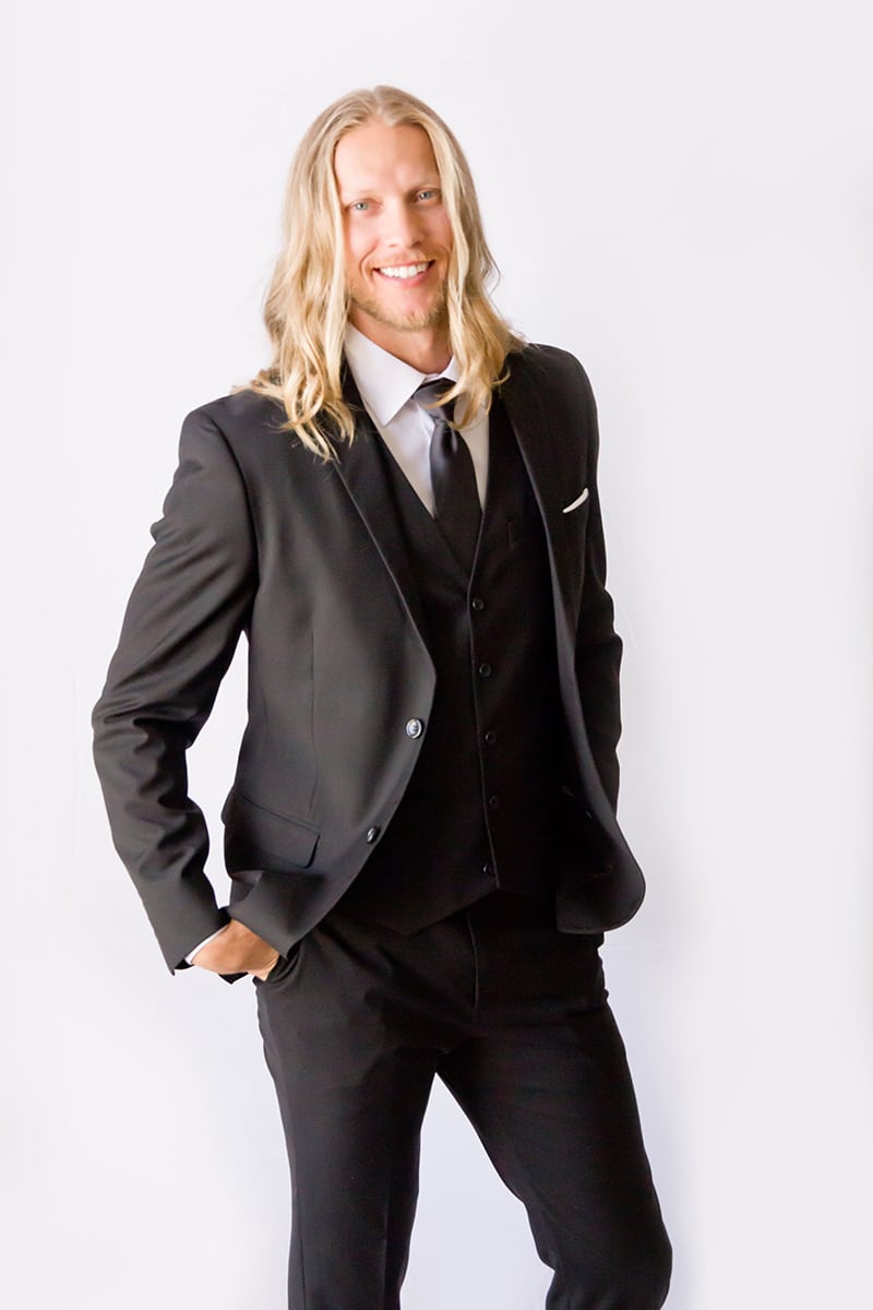 Groom smiling, shows off his black suit from Modern Groom.