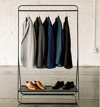Assorted colors of Modern Groom jackets hang on a suit stand.