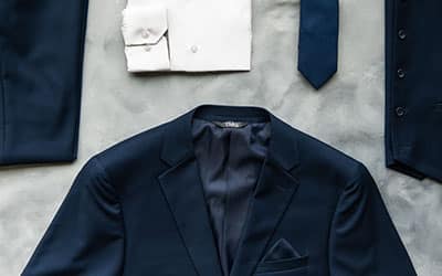 Overhead view of Modern Groom attire neatly placed on a table surface, including suit pants, jacket, vest, cuffs, and tie.