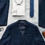 Overhead view of what is included in Modern Groom's full suit package. Package includes jacket, vest, pants, shirt, tie, pocket square, shoes, belt, and socks.