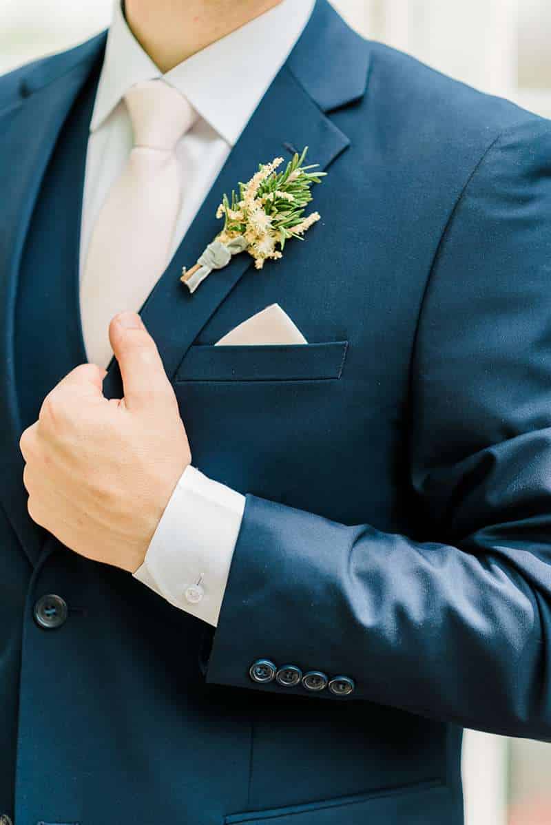 Man wearing a blue wedding suit with a boutonniere.