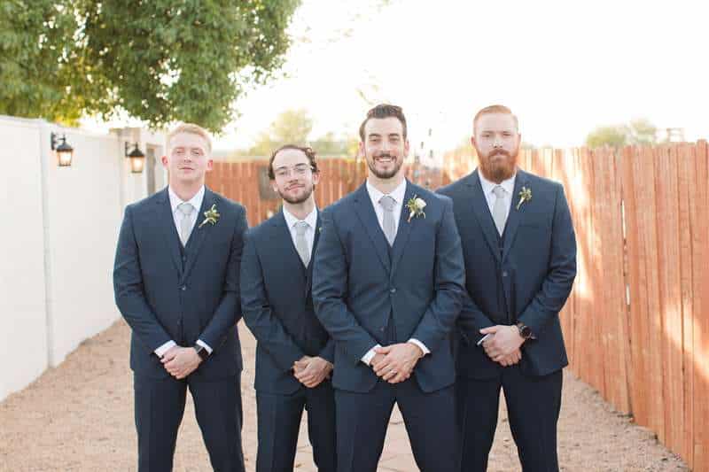 A groom and his groomsmen pose in matching charcoal suits.