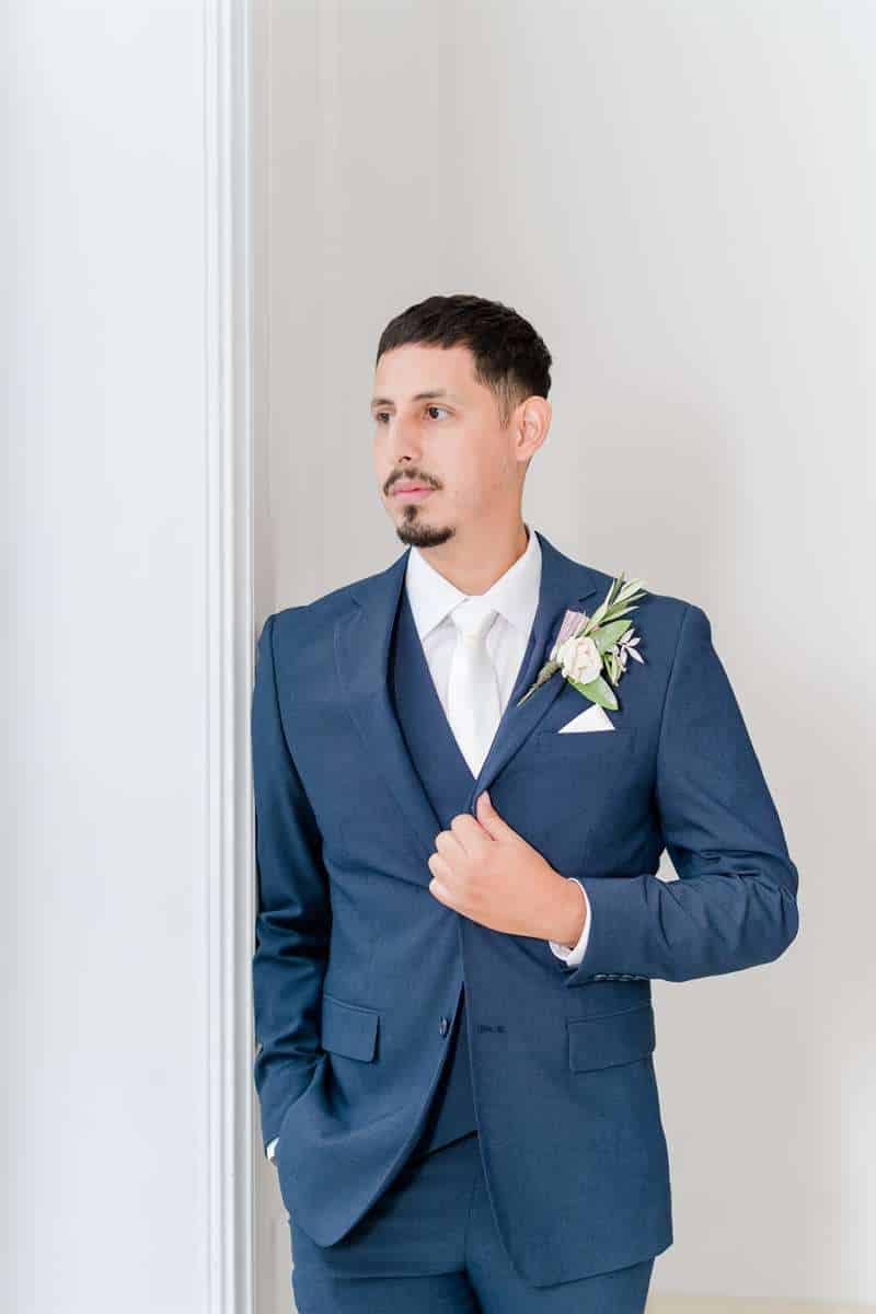A man poses in his light-blue wedding suit.
