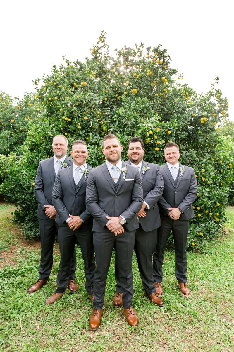 A groom and his groomsmen pose in charcoal grey suits.