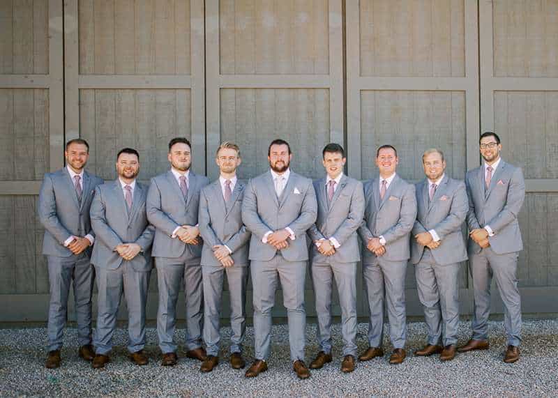 A groom and his groomsmen pose in matching light-gray suits.