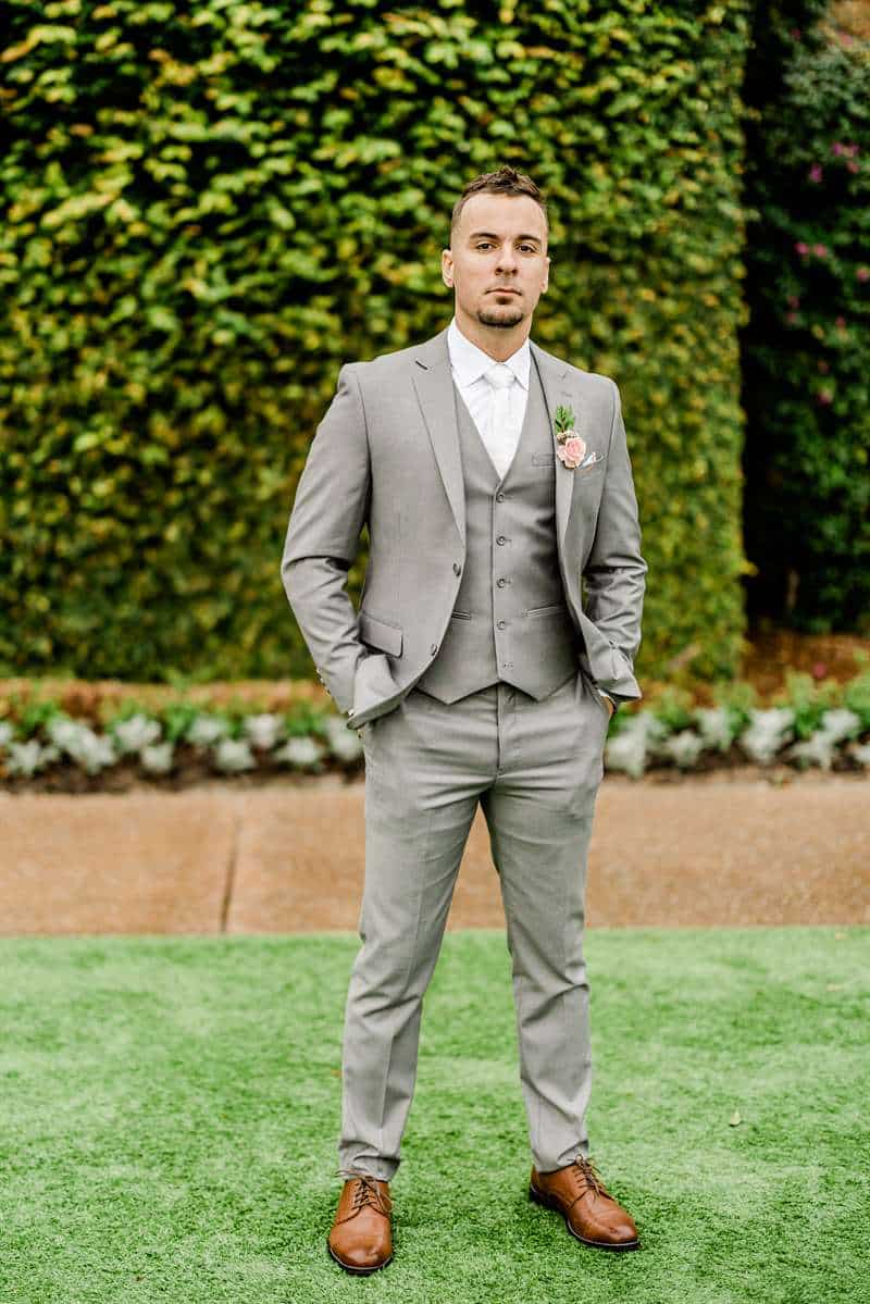 Man posing in a modern groom suit on the grass.