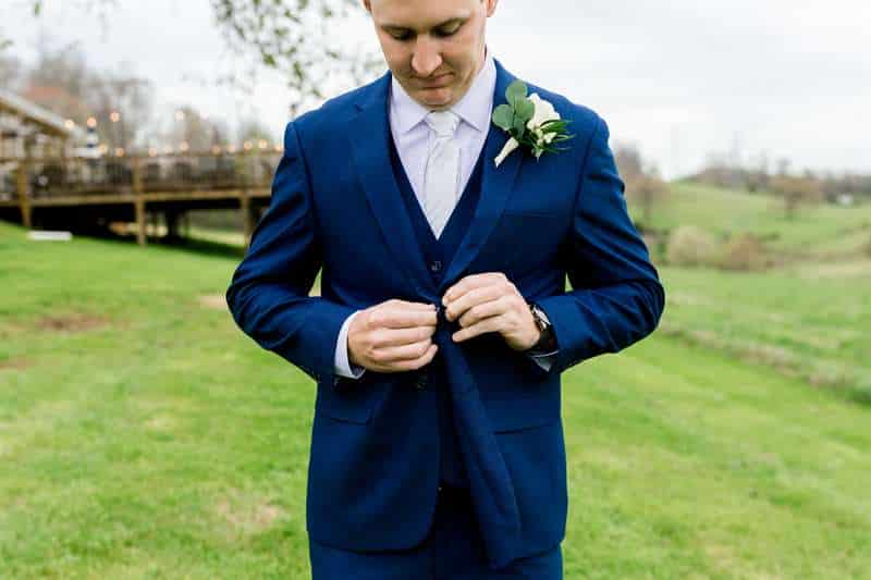 The groom adjusts his blue suit.