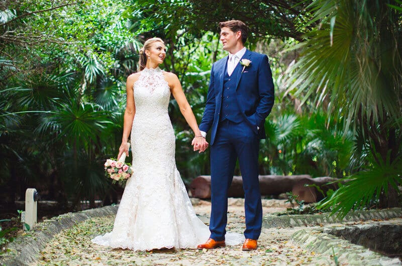 Bride and groom holding hands on a path in a garden.