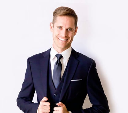 Cropped view of a young man in a navy blue wedding suit.