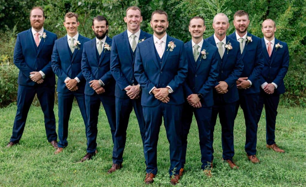 Groomsmen standing in formation behind the groom in matching suits