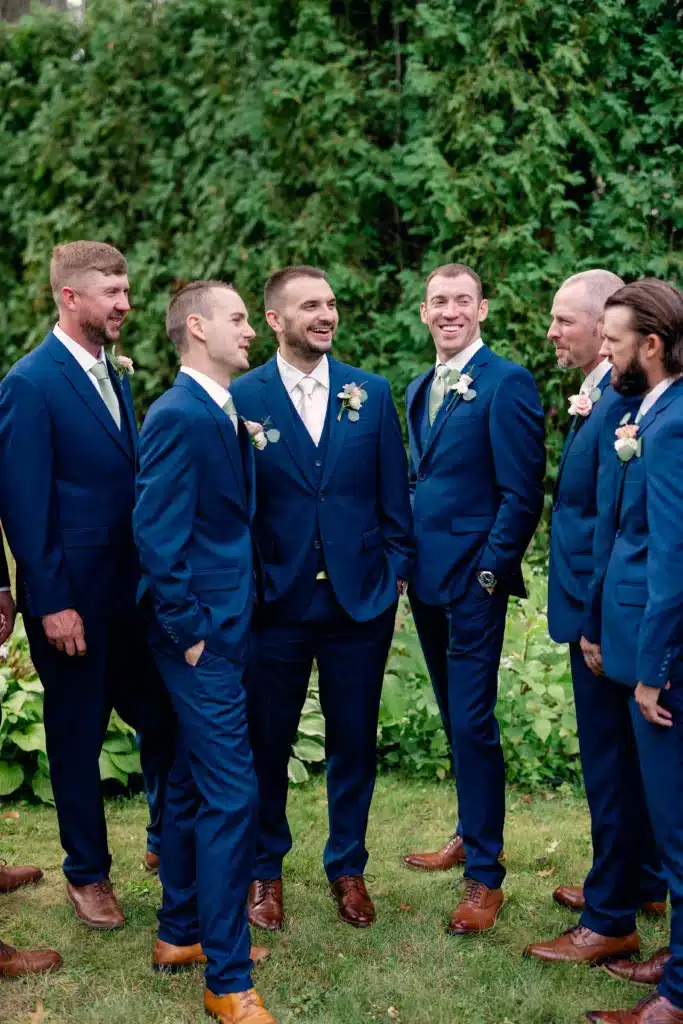A groom and groomsmen in midnight blue wedding suits and brown shoes
