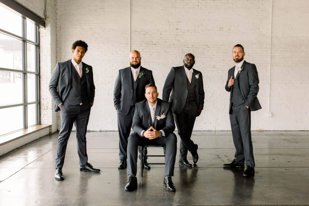 four groomsmen surrounding a groom with matching suits and shoes