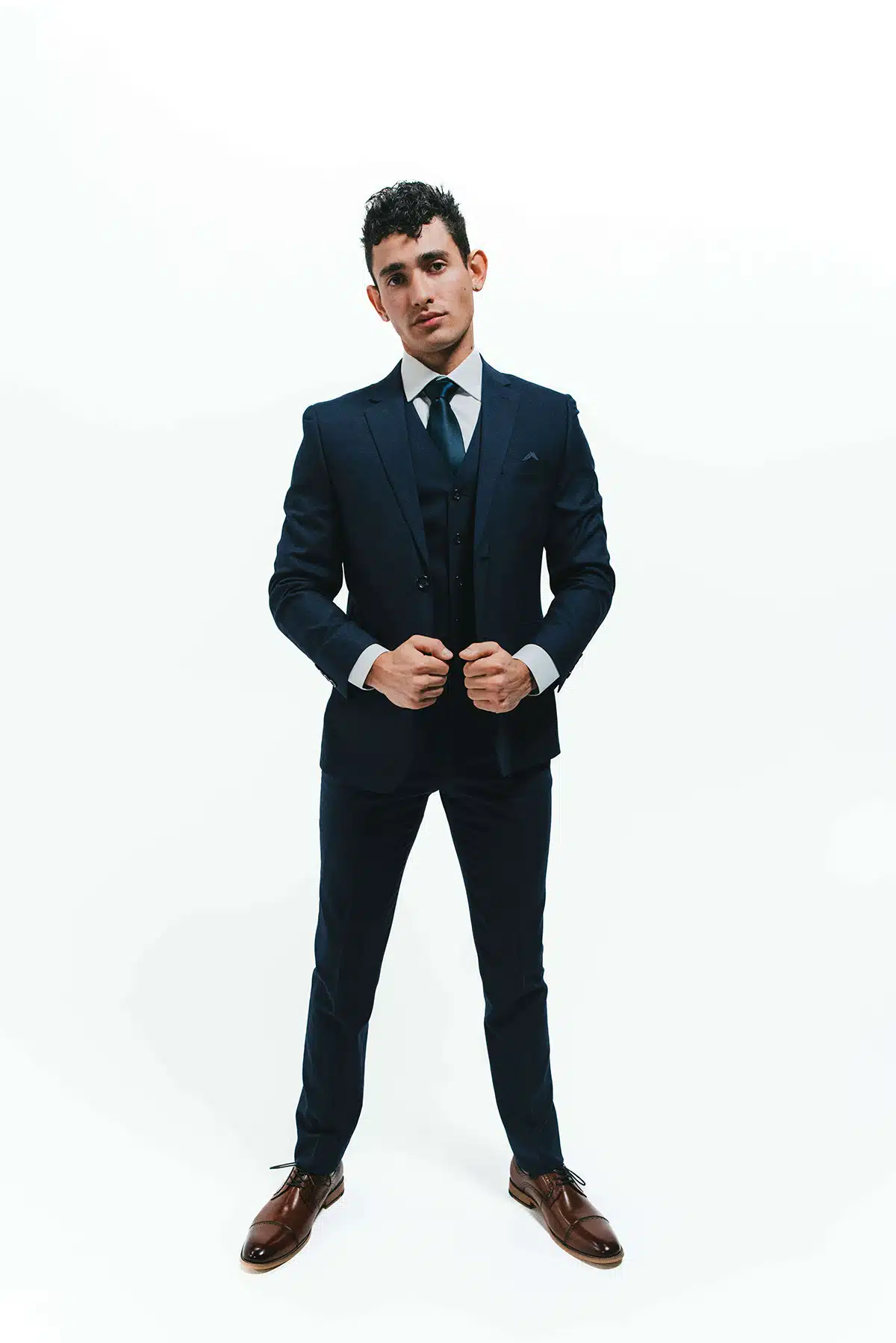 Groom wearing a Heathered Navy winter wedding suit against a white backdrop
