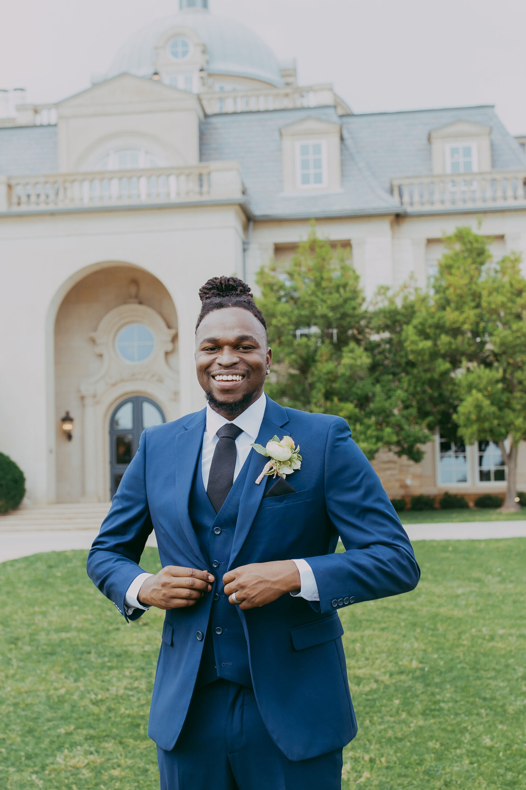 A groom wearing a three-piece midnight navy blue spring wedding suit on his wedding day
