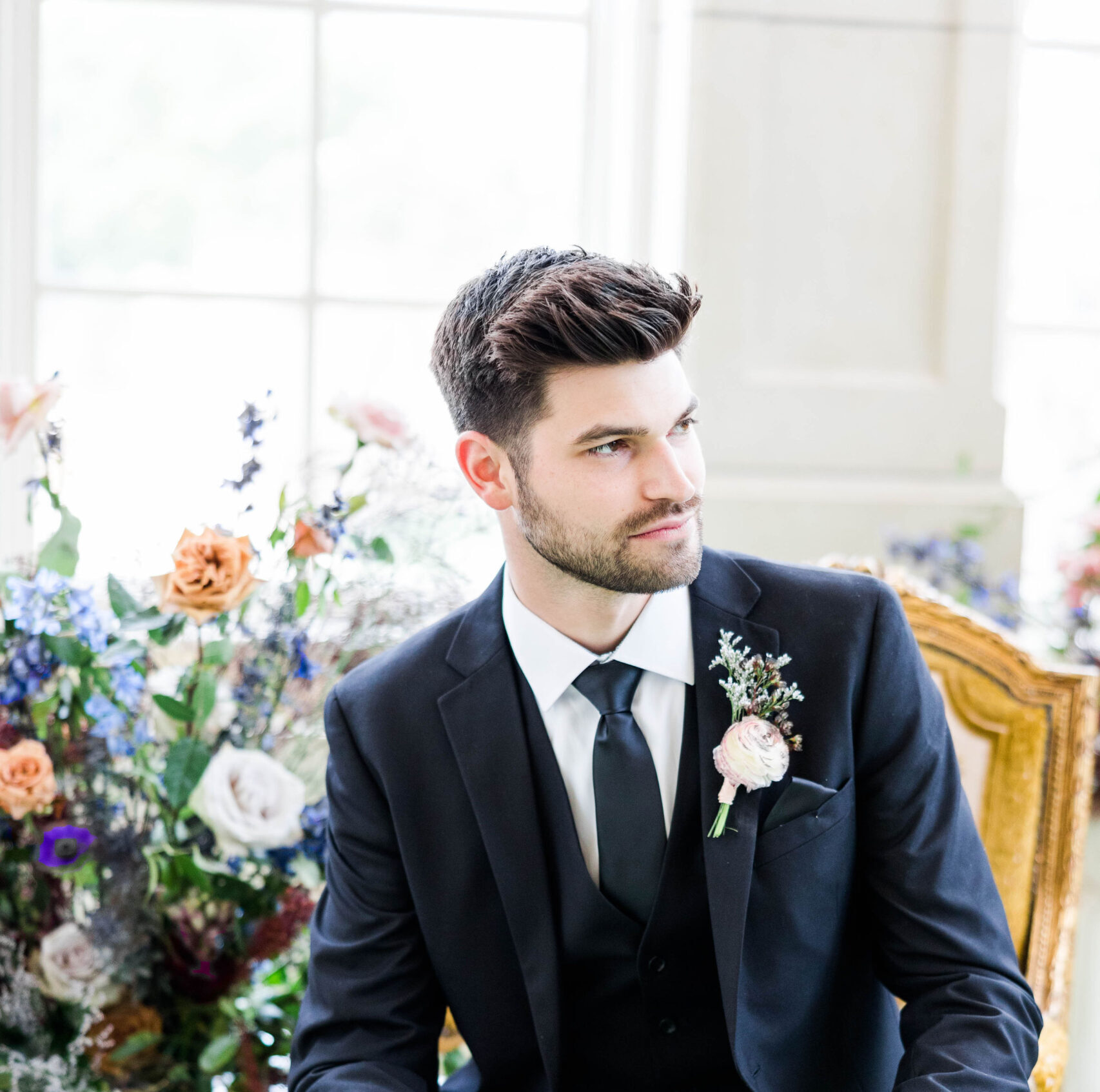 Groom sitting in a dark fall wedding suit and tie waiting for his bride