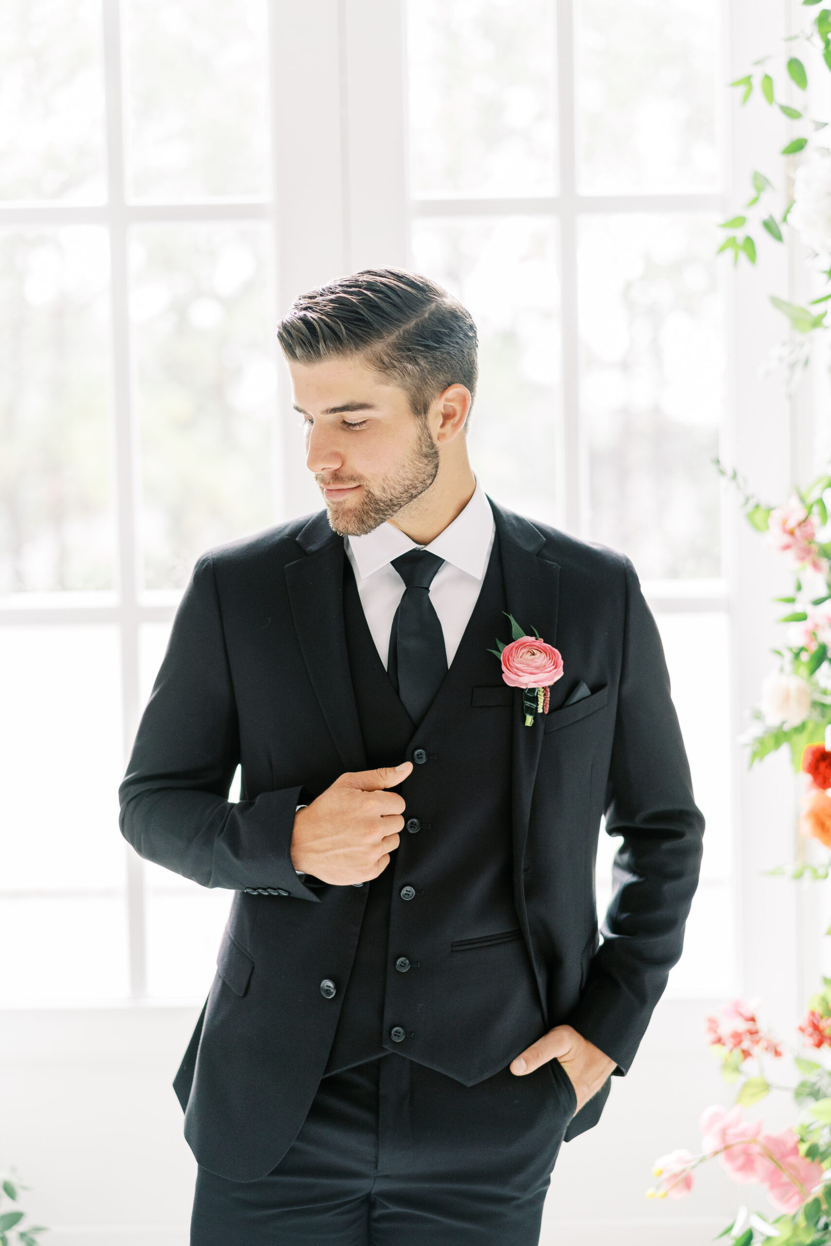 A groom in a black suit posing in a well-lit room